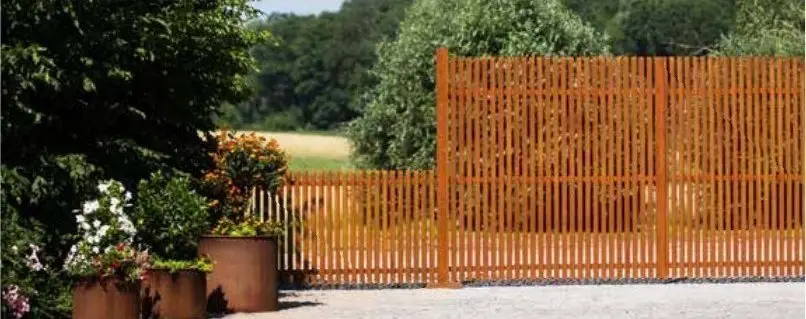 Gartenzaun aus Cortenstahl mit Pflanzgefäßen davor
