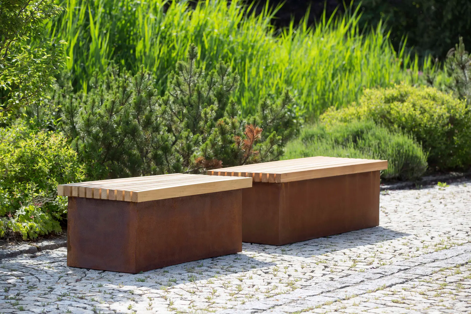 Offene Sitzbänke aus Cortenstahl mit Holzauflage im Garten